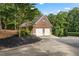 Spacious two-car brick garage featuring white doors and a concrete driveway, surrounded by lush greenery and landscaped mulch at 110 Wellington Way, Canton, GA 30115