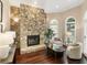 Cozy living room featuring a stone fireplace, hardwood floors, and arched windows for natural light at 110 Wellington Way, Canton, GA 30115