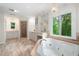 Bright bathroom featuring a jacuzzi tub next to a large window, and a shower with a glass door at 313 Clubhouse Nw Ct, Kennesaw, GA 30144