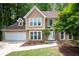 Stunning two-story house featuring lush greenery, a spacious driveway, and a charming stone-accented entrance at 313 Clubhouse Nw Ct, Kennesaw, GA 30144