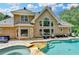 Expansive back of home with multiple windows, outdoor seating, inground pool and spa with beautiful landscaping at 5980 Whitestone Ln, Suwanee, GA 30024