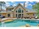Expansive back of home with multiple windows, outdoor seating, inground pool and spa with beautiful landscaping at 5980 Whitestone Ln, Suwanee, GA 30024