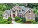 Stately tan home with a gray roof, arched windows, and manicured landscaping offering curb appeal at 5980 Whitestone Ln, Suwanee, GA 30024