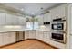 Bright kitchen features white cabinets, stainless steel appliances and hardwood floors at 5980 Whitestone Ln, Suwanee, GA 30024