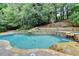 Beautiful pool and spa with waterfall feature, surrounded by lush landscaping and mature trees at 5980 Whitestone Ln, Suwanee, GA 30024