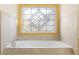 Close-up of a large soaking tub with tiled surround and decorative glass window at 971 Ashebrooke Ne Ct, Marietta, GA 30068