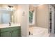 Bright bathroom with white countertops, green cabinetry, a soaking tub, and modern fixtures at 395 Grove Ridge Dr, Loganville, GA 30052