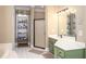 Well-lit bathroom with green cabinetry, white countertops, shower and shelving unit at 395 Grove Ridge Dr, Loganville, GA 30052