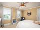 Cozy bedroom featuring a baseball-themed ceiling fan, two windows and neutral decor at 395 Grove Ridge Dr, Loganville, GA 30052
