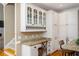 Elegant kitchen area with desk, granite countertop, white cabinets, and glass-front display cabinets at 395 Grove Ridge Dr, Loganville, GA 30052