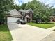 Charming brick home with a two-car garage and lush, green front lawn with mature trees at 627 Arbour Way, Suwanee, GA 30024