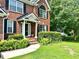 Close up of charming brick home's front door with lush manicured front yard and mature tree at 627 Arbour Way, Suwanee, GA 30024