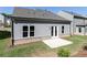 View of the home's backyard with a concrete patio, windows, and gray siding at 1517 Ellie Ridge Ave, Lawrenceville, GA 30043