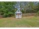 Charming backyard shed painted light blue with a pink door and white trim near a wooded perimeter at 6341 Stewart Ridge Walk, Buford, GA 30518