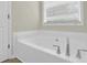 Large white bathtub with modern silver fixtures next to a window and white door at 6341 Stewart Ridge Walk, Buford, GA 30518