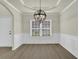 The dining room features hardwood floors, neutral paint, wainscotting, a modern light fixture, and a view into the entry at 6341 Stewart Ridge Walk, Buford, GA 30518