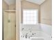 Bathroom boasting a jetted tub, white tile, and a glass enclosed shower at 130 Nicki Ct, Hampton, GA 30228