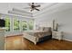 Bright main bedroom with tray ceiling, hardwood floors, a king-size bed, and large windows overlooking the yard at 4381 Laurian Nw Dr, Kennesaw, GA 30144