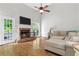 Open living room with hardwood floors, brick fireplace, and a large sectional sofa with French doors opening to a deck at 4381 Laurian Nw Dr, Kennesaw, GA 30144