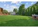Expansive backyard featuring lush green grass, mature trees, playhouse, and a wooden deck at 7025 Coffield Ct, Cumming, GA 30041