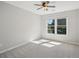 Bright bedroom featuring a window, a ceiling fan, and neutral walls with clean carpeting at 7025 Coffield Ct, Cumming, GA 30041