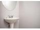 Small half bath with a pedestal sink and round mirror at 2544 Castellan Dr, Atlanta, GA 30316
