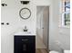Updated bathroom with dark blue vanity and round mirror, and white tiled shower and walls at 4172 N Martin Way, Lithia Springs, GA 30122
