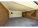 Covered parking area with brick walls and concrete floor, featuring a white door to enter the home at 4172 N Martin Way, Lithia Springs, GA 30122