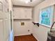 Well-lit laundry room featuring a window, storage cabinets, and laminate flooring at 60 Parkman Trl, Covington, GA 30016