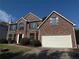 Two-story brick home with large windows, a two-car garage, and well-maintained landscaping at 7097 Cavender Sw Dr, Atlanta, GA 30331