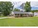 Well-manicured front yard with a single story brick house, manicured lawn and mature trees at 3642 S Bogan Rd, Buford, GA 30519