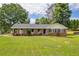 Charming brick home featuring a well-manicured lawn and a welcoming front porch with beautiful trees at 3642 S Bogan Rd, Buford, GA 30519