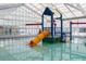 Bright indoor pool area featuring a colorful waterslide and ample natural light from the skylight roof at 3642 S Bogan Rd, Buford, GA 30519