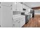 Kitchen features white cabinets, black appliances, and wood-look flooring at 3642 S Bogan Rd, Buford, GA 30519