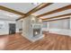 Open concept living area with a central fireplace, hardwood floors, and exposed beams, great for entertaining at 3642 S Bogan Rd, Buford, GA 30519