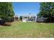Expansive backyard with a lush lawn, mature trees, a fire pit, and a white two-story home at 130 Bevington Ln, Woodstock, GA 30188