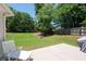 Expansive backyard features a well-maintained lawn, mature trees, wooden fence and a charming patio with a white lounge chair at 130 Bevington Ln, Woodstock, GA 30188