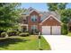 Traditional brick two-story home featuring a manicured lawn, an attached two-car garage and mature trees at 130 Bevington Ln, Woodstock, GA 30188