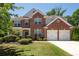 Traditional brick two-story home featuring a manicured lawn, an attached two-car garage and mature trees at 130 Bevington Ln, Woodstock, GA 30188