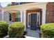 Charming covered front porch with a dark front door, brick columns and manicured landscaping at 130 Bevington Ln, Woodstock, GA 30188