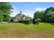 Lush green backyard with mature trees and view of the home's rear elevation with a 2-car garage at 4440 Green Summers Dr, Cumming, GA 30028