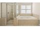 Bathroom featuring tiled shower, jacuzzi tub, and window providing natural light at 4440 Green Summers Dr, Cumming, GA 30028