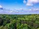 Expansive aerial view of lush green treetops beneath a bright blue sky with scattered white clouds at 466 Thackery Sw Pl, Atlanta, GA 30311