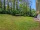 Lush green backyard with mature trees providing privacy and a view of the home's exterior at 466 Thackery Sw Pl, Atlanta, GA 30311