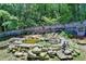 Wooded backyard featuring a rock-lined pond with waterfall and wishing well at 4751 Shay Ter, Buford, GA 30519