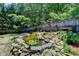 Lush backyard with a rock bordered pond featuring a waterfall and vibrant plant life at 4751 Shay Ter, Buford, GA 30519