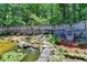 Beautiful backyard pond with waterfall feature and lush landscaping surrounded by a privacy fence at 4751 Shay Ter, Buford, GA 30519