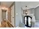 Inviting hallway with beautiful wood floors and modern lighting fixtures, leading to the home's entrance with striking black doors at 4751 Shay Ter, Buford, GA 30519