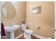 Half bathroom with modern pedestal sink, oval mirror, white toilet, and wood look floors at 3476 Bridge Walk Drive, Lawrenceville, GA 30044