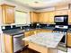 Bright kitchen featuring oak cabinets, black countertops, and a granite island at 665 Roxford Ln, Buford, GA 30518